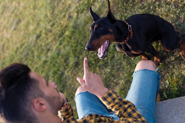 Beau jeune homme joue avec son chien dans le parc.