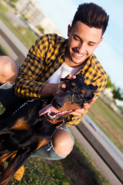 Beau jeune homme joue avec son chien dans le parc.