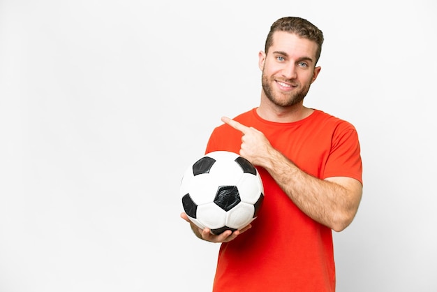 Beau jeune homme de joueur de football sur fond blanc isolé pointant vers le côté pour présenter un produit