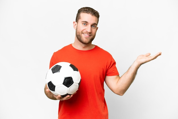 Beau jeune homme de joueur de football sur fond blanc isolé tendant les mains sur le côté pour inviter à venir