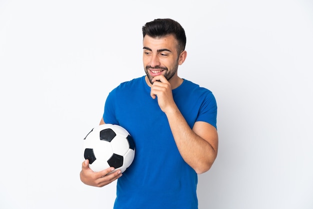 Beau jeune homme joueur de football sur un mur isolé regardant sur le côté et souriant