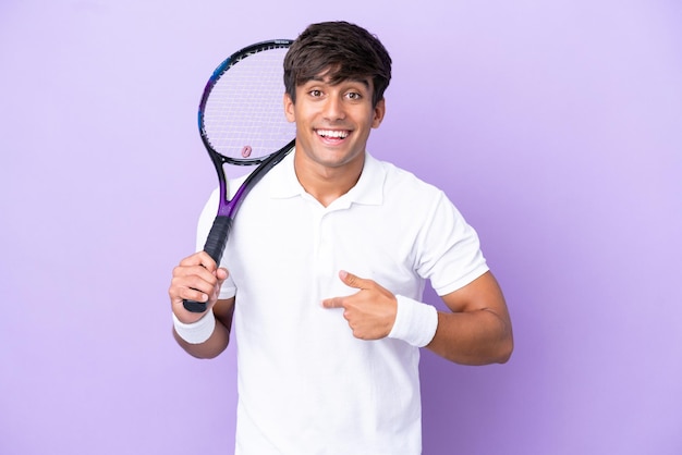 Beau jeune homme de joueur de tennis isolé sur fond ocre avec une expression faciale surprise