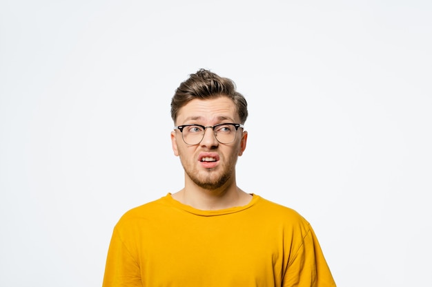 Beau jeune homme à lunettes choqué avec une expression de surprise