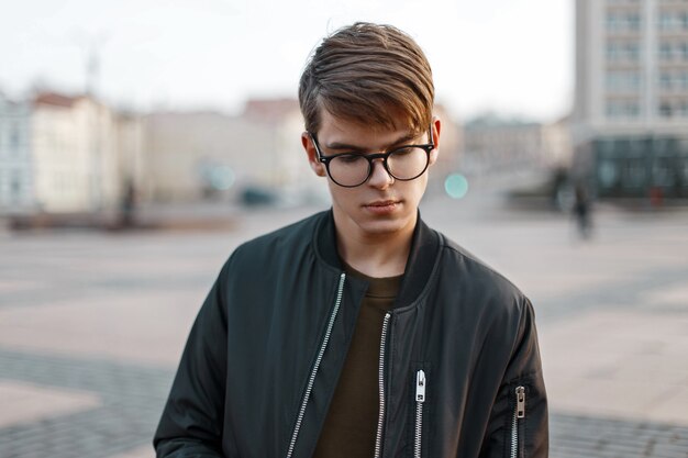 Beau jeune homme avec des lunettes sur le fond de la ville