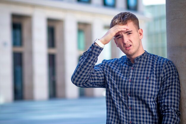 Beau jeune homme malade, un malade souffre de maux de tête, de fièvre. Fatigué, épuisé, la tête, le front avec la main. Mauvais sentiment négatif de désespoir, d'apathie.