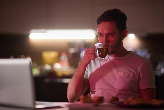 Beau jeune homme mangeant des aliments malsains en regardant un film la nuit