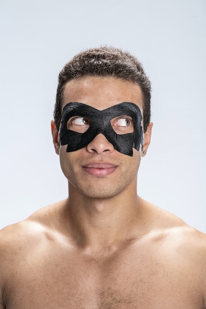 Beau jeune homme avec un masque noir autour des yeux en détournant les yeux