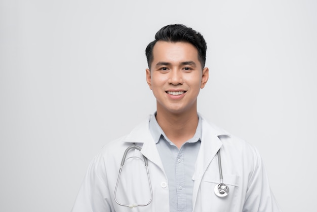 Beau jeune homme médecin souriant à côté et regardant loin en pensant.