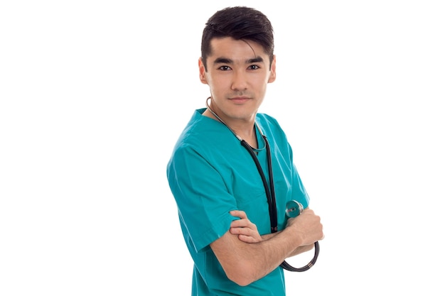 Beau jeune homme médecin avec stéthoscope en uniforme posant isolé sur fond blanc