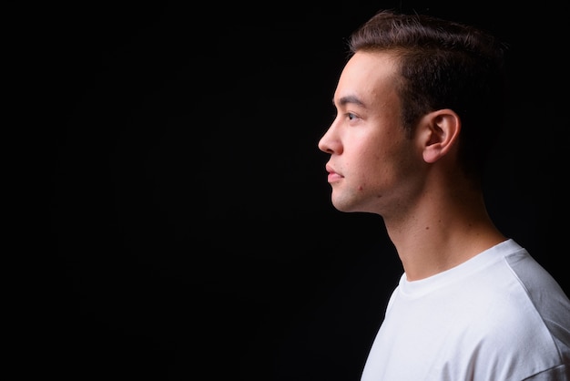 Beau jeune homme multiethnique contre le mur noir