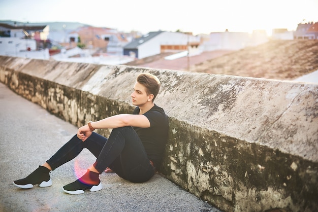 Beau jeune homme en noir posant dans la rue