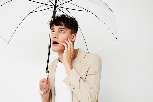 Beau jeune homme avec un parapluie ouvert dans un fond clair de costume