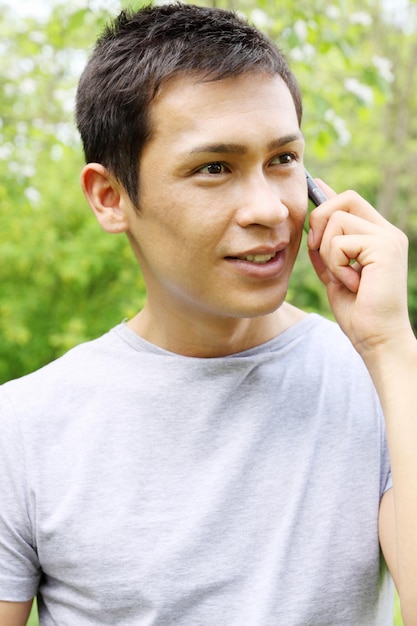 Beau jeune homme parle sur un téléphone portable