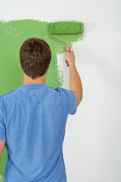 beau jeune homme peint en bleu et vert couleur mur blanc de la nouvelle maison