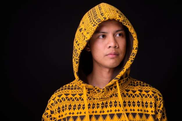 Photo beau jeune homme philippin portant un sweat à capuche contre le mur noir