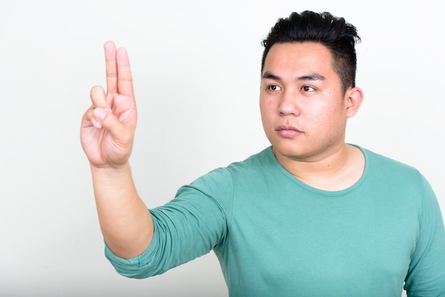 Beau jeune homme philippin en surpoids contre le mur blanc