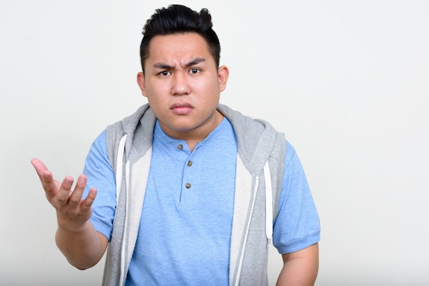 Beau jeune homme philippin en surpoids contre le mur blanc