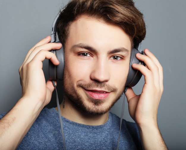 Beau jeune homme portant des écouteurs et écouter de la musique.