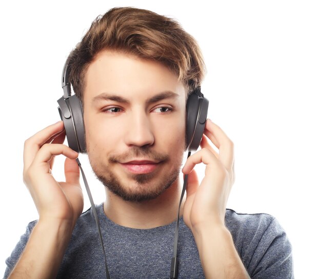 Beau jeune homme portant des écouteurs et souriant debout