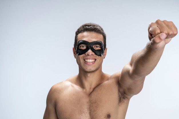 Beau jeune homme portant un masque facial levant la main et souriant