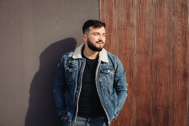 Beau jeune homme posant à côté du mur