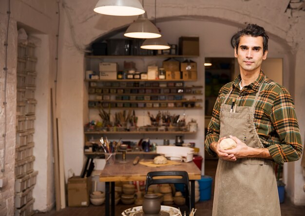 Beau jeune homme posant dans un atelier de poterie