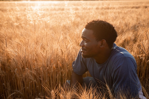 Beau jeune homme positif dans un champ de céréales