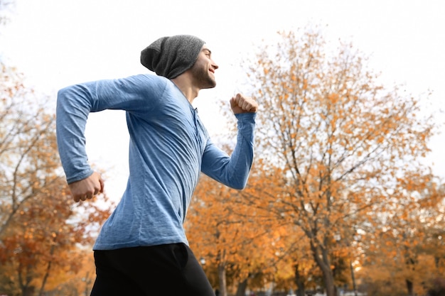 Beau jeune homme qui court dans le magnifique parc d'automne