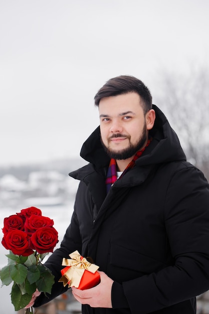 Beau jeune homme romantique avec bouquet de roses rouges dans les mains