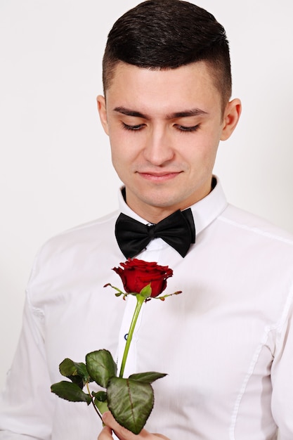 Beau jeune homme avec une rose rouge le jour de la Saint-Valentin
