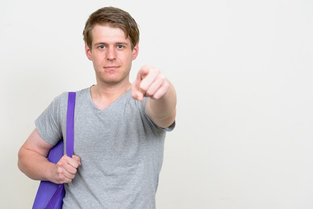 Beau jeune homme scandinave prêt pour la salle de sport contre le mur blanc