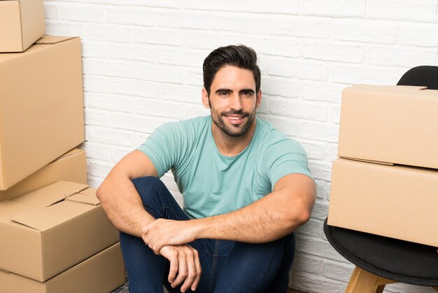 Beau jeune homme se déplaçant dans la nouvelle maison parmi les boîtes