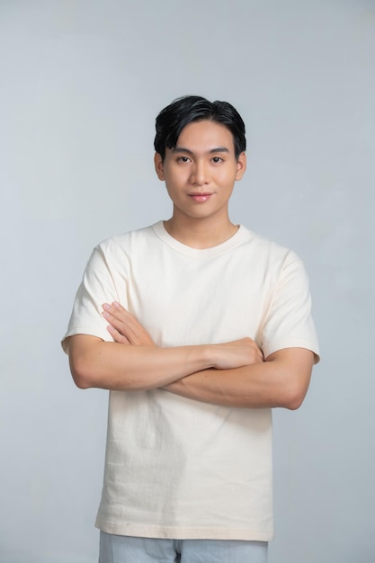 Beau jeune homme souriant avec les bras croisés sur fond blanc