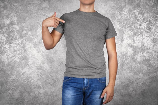 Beau jeune homme en t-shirt gris blanc debout contre un mur texturé se bouchent