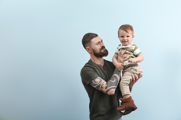 Beau jeune homme tatoué tenant un petit garçon mignon