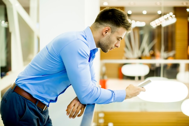 Beau jeune homme avec un téléphone portable au bureau