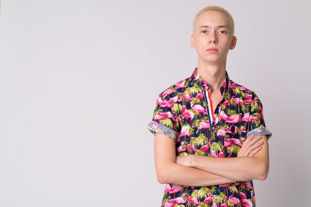 Beau jeune homme touriste androgyne en chemise bohème contre le mur blanc