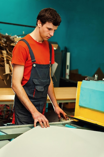 Beau jeune homme travaillant dans la fabrication avec des boîtes à l'usine pour la production d'emballages en carton