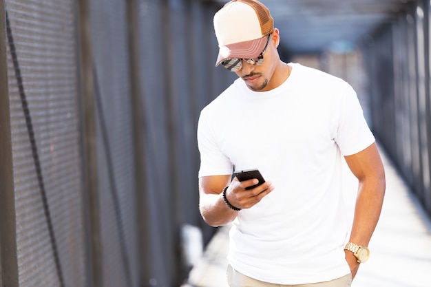 Beau jeune homme utilisant son téléphone portable dans la rue.