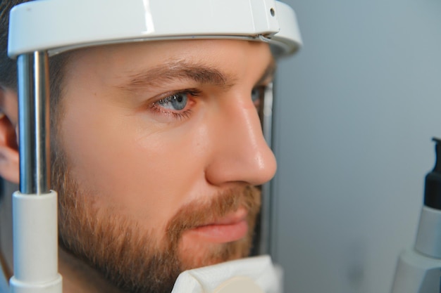 Beau jeune homme vérifie la vision des yeux dans une clinique d'ophtalmologie moderne Patient dans une clinique d'ophtalmologie