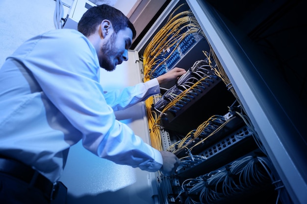 Beau jeune ingénieur travaillant dans la salle des serveurs