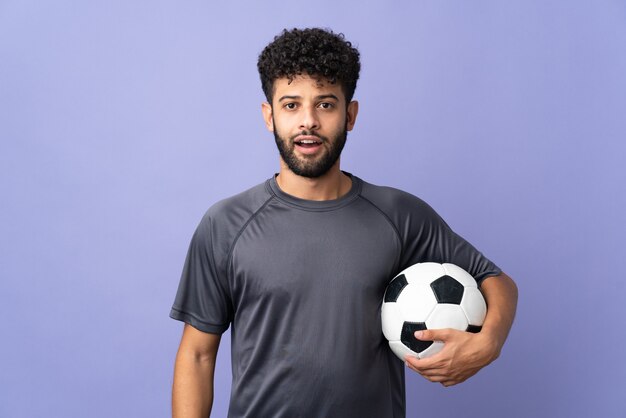 Beau jeune joueur de football marocain homme sur violet avec expression faciale surprise