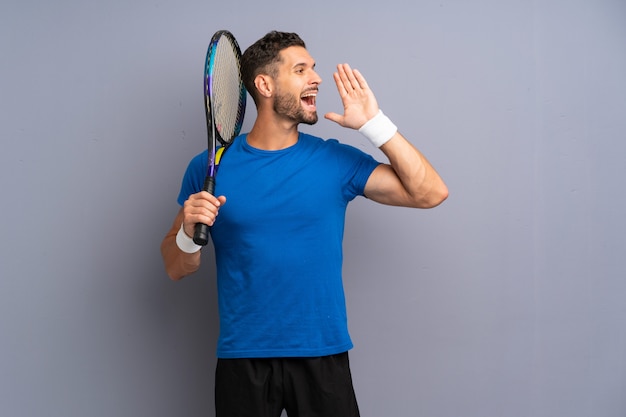 Beau jeune joueur de tennis homme criant avec la bouche grande ouverte