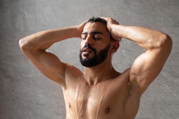 Beau jeune mannequin arabe prenant une douche chaude