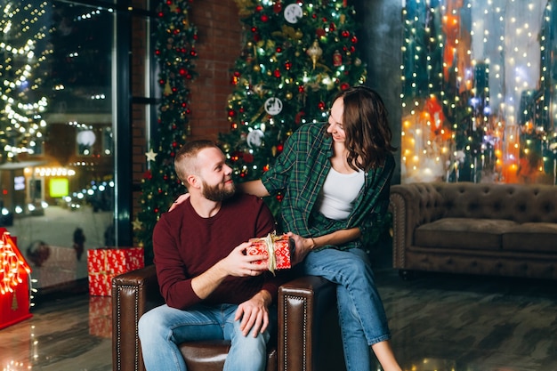 Beau jeune mari et femme de la famille donnent des cadeaux à l'arbre de Noël