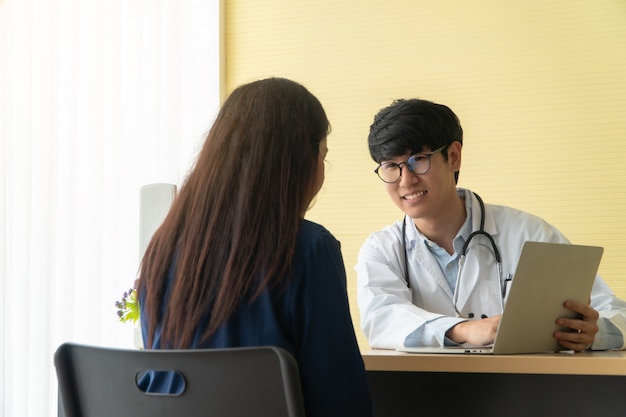 Beau et jeune médecin donnant une consultation à un patient et montrant des informations médicales