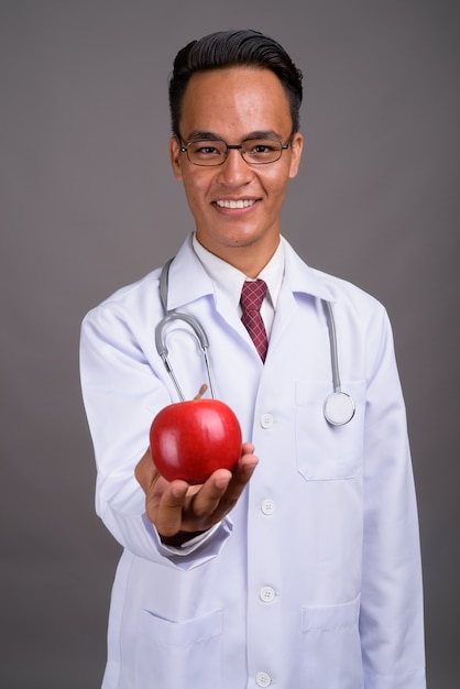 Beau jeune médecin indien contre le mur gris