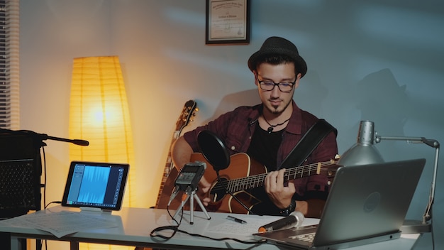 Beau jeune musicien enregistrant sa nouvelle piste en home studio