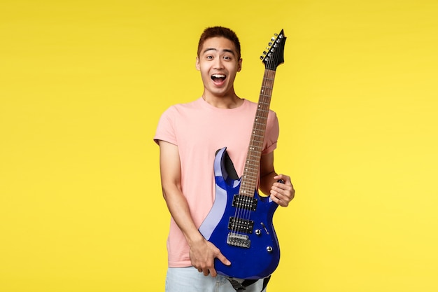 Beau jeune musicien jouant de la guitare et chantant, isolé