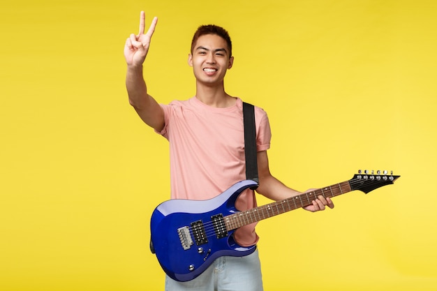 Beau jeune musicien jouant de la guitare et chantant